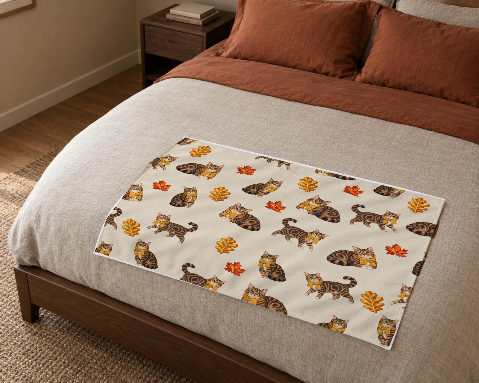 Autumn Cat Naps blanket spread across a bed, showing brown tabby cats wearing mustard-gold scarves among copper maple leaves and golden oak leaves on warm oatmeal.