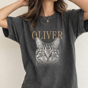 A woman wearing a Pepper Comfort Colors 1717 T-shirt with Oliver’s portrait and OLIVER in warm tan serif letters; the exact approved artwork is placed on the shirt.