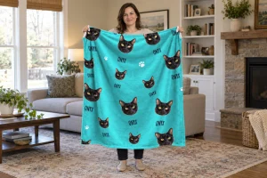 Woman holding a turquoise personalized cat face blanket with larger Onyx portraits, matching names and white paw prints.