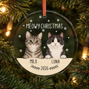 Transparent faceted glass Christmas ornament with Milo and Luna cat portraits, white Meowy Christmas lettering and a red ribbon on a Christmas tree