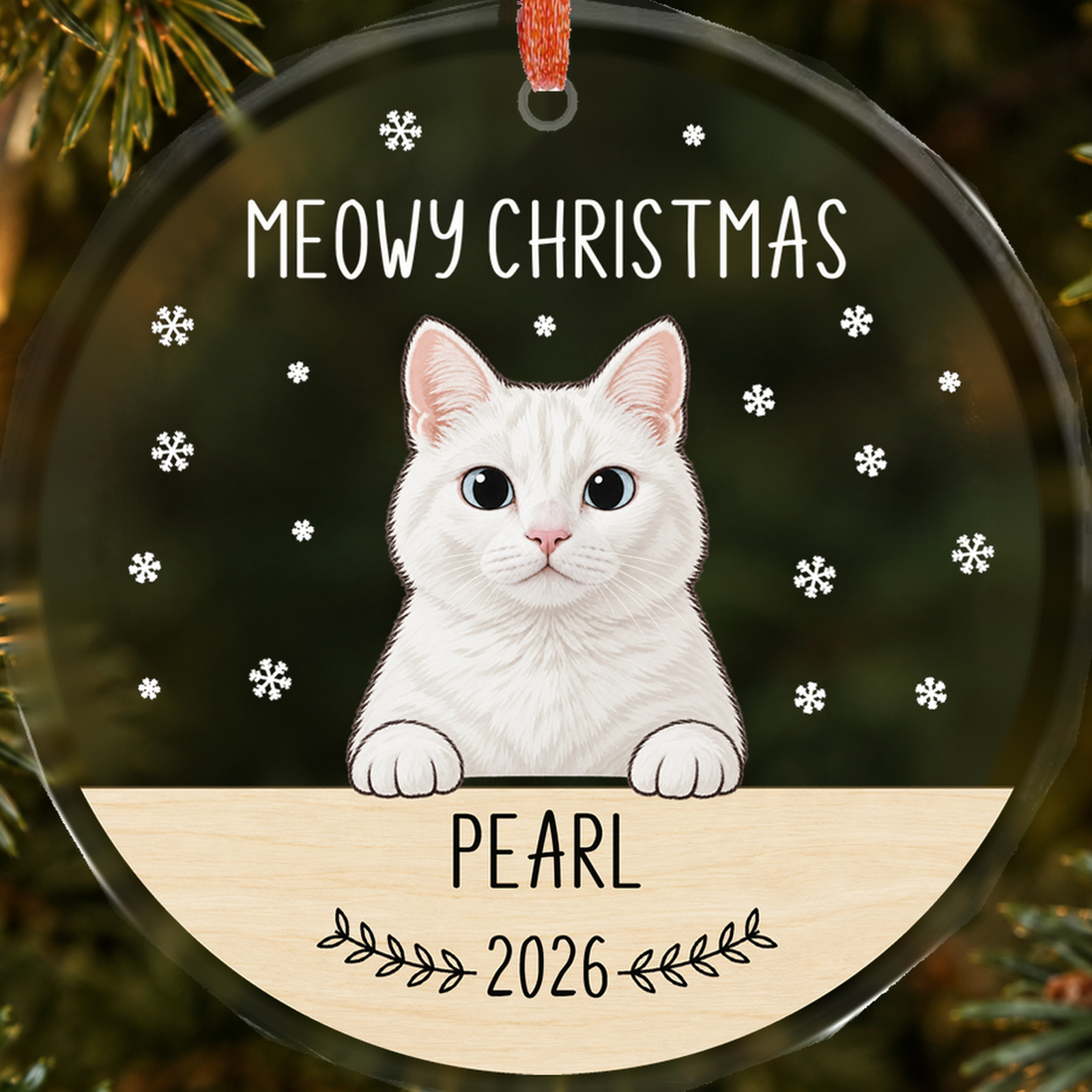 Close-up of Pearl cat portrait and name, white snowflakes and 2026 on a transparent faceted glass Christmas ornament
