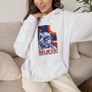Person wearing a hoodie showing a gray tabby astronaut, a ringed golden planet and stars on deep blue