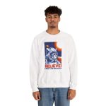 Person wearing a crewneck sweatshirt showing a gray tabby astronaut, a ringed golden planet and stars on deep blue Person wearing a crewneck sweatshirt showing a gray tabby astronaut, a ringed golden planet and stars on deep blue