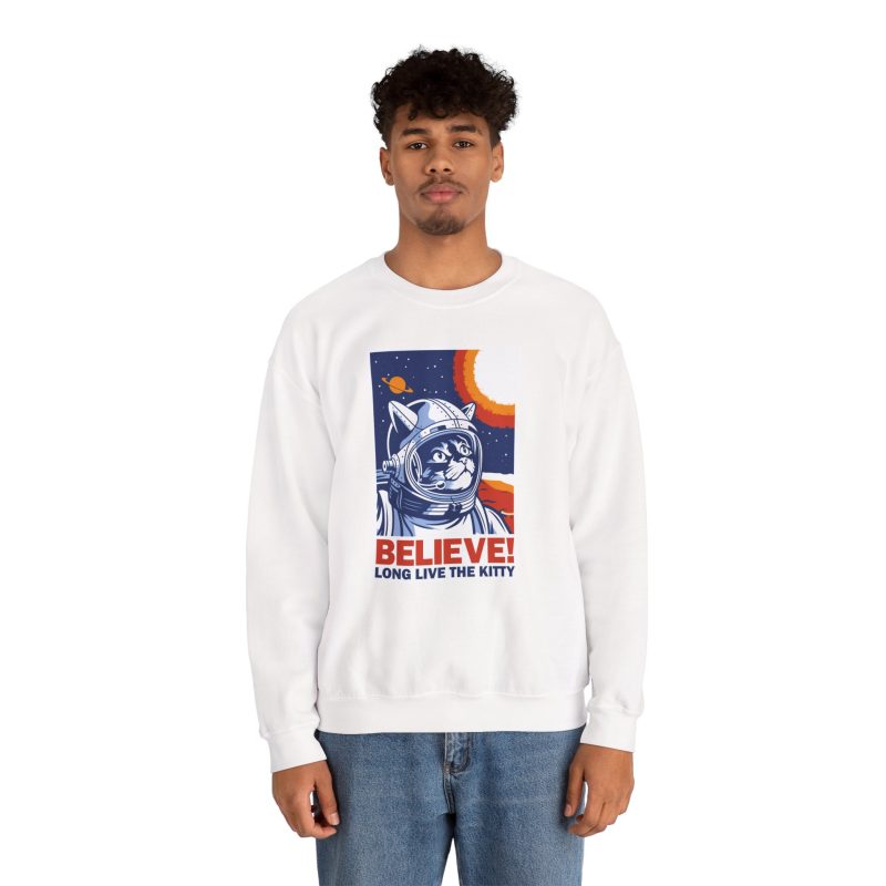 Person wearing a crewneck sweatshirt showing a gray tabby astronaut, a ringed golden planet and stars on deep blue