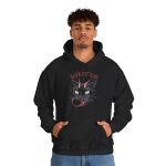 Person wearing a hoodie showing a horned black cat with green eyes, a curling red tongue and angular red lettering