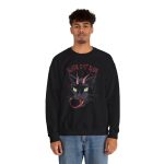 Person wearing a crewneck sweatshirt showing a horned black cat with green eyes, a curling red tongue and angular red lettering