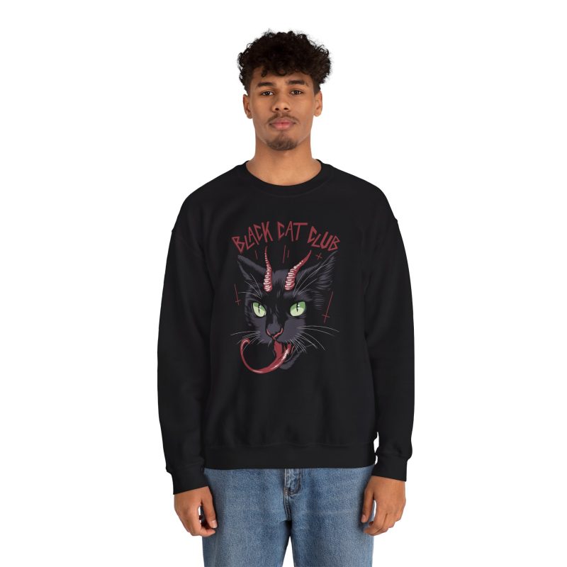 Person wearing a crewneck sweatshirt showing a horned black cat with green eyes, a curling red tongue and angular red lettering