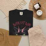 Close view of a horned black cat with green eyes, a curling red tongue and angular red lettering in the front print
