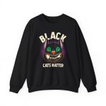 Front of the crewneck sweatshirt showing a grinning black cat with huge green eyes, orange mouth outlines and a purple halo