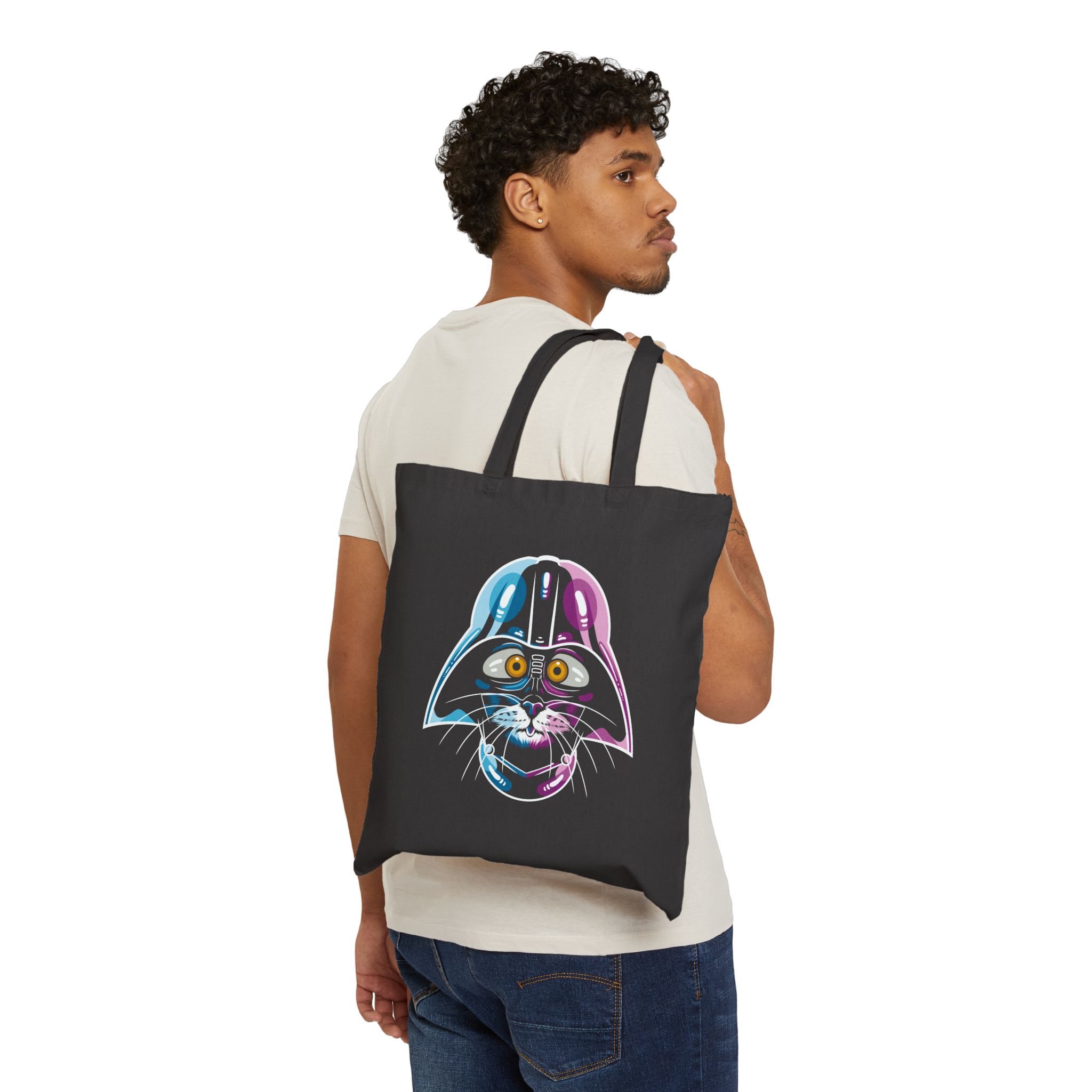 Person carrying a black canvas tote showing an amber-eyed cat in a dark sci-fi helmet with cyan, magenta and white highlights