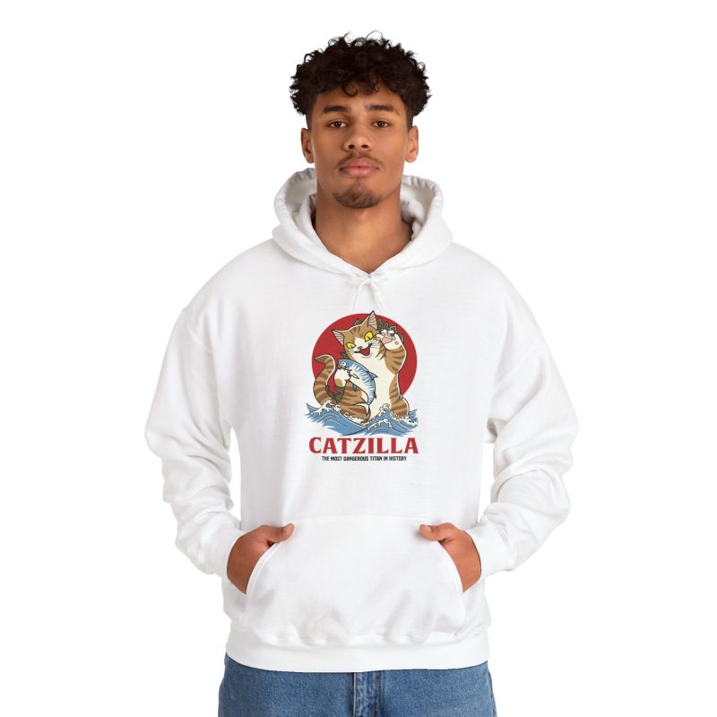 Person wearing a hoodie showing a giant brown tabby holding a blue fish above waves in front of a red sun disc