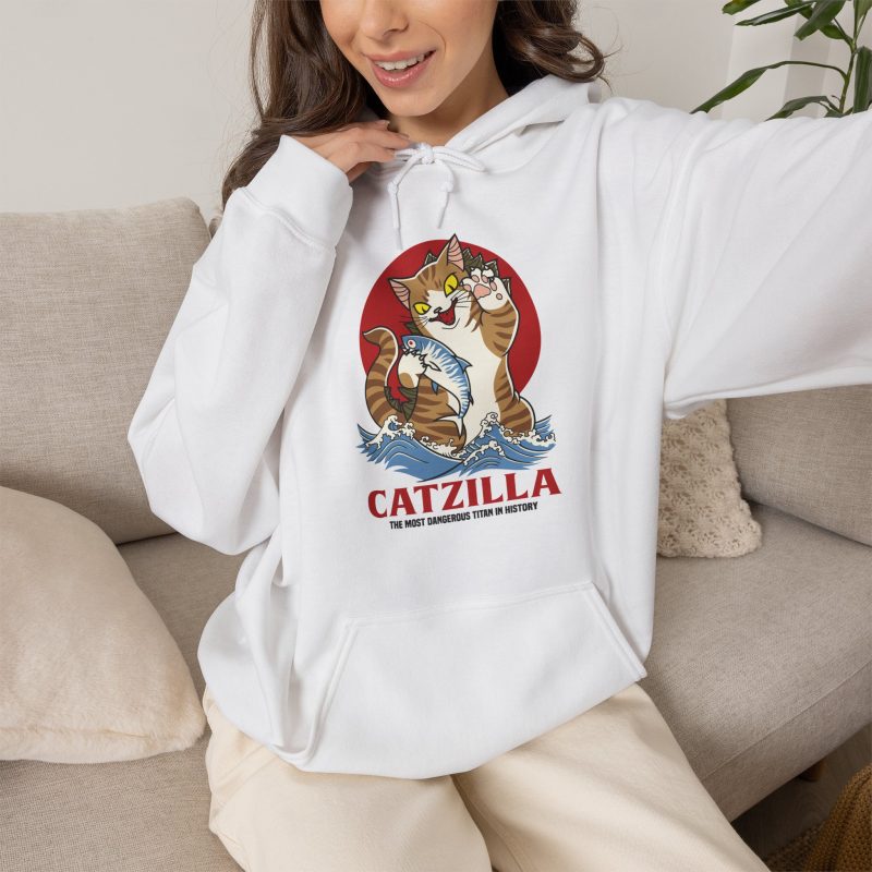 Person wearing a hoodie showing a giant brown tabby holding a blue fish above waves in front of a red sun disc
