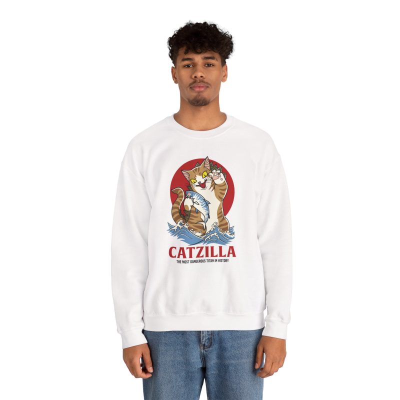 Person wearing a crewneck sweatshirt showing a giant brown tabby holding a blue fish above waves in front of a red sun disc