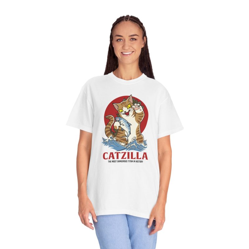Person wearing a tee showing a giant brown tabby holding a blue fish above waves in front of a red sun disc