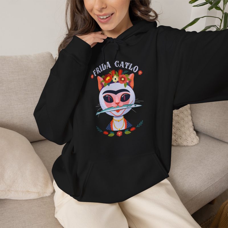 Person wearing a hoodie with a pale pink cat with a unibrow, a flower crown, gold beads and a teal fish printed on the front