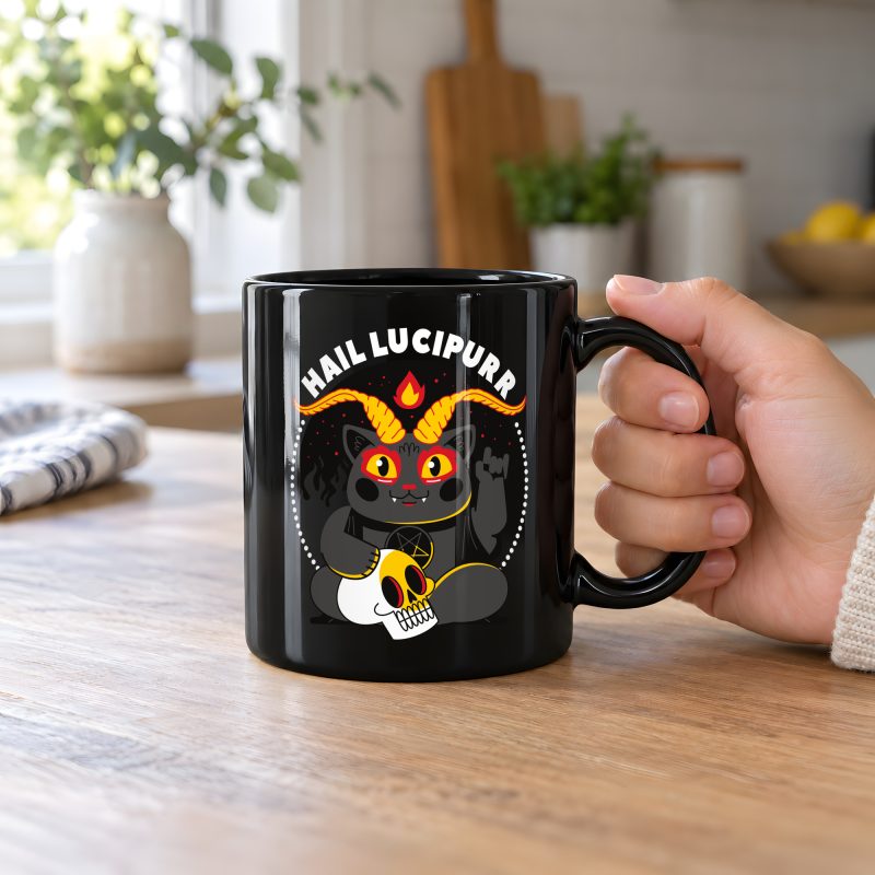 Person holding a glossy black ceramic mug showing a dark gray horned cat with yellow eyes, a skull, a pentagram and a flame inside a white dotted circle