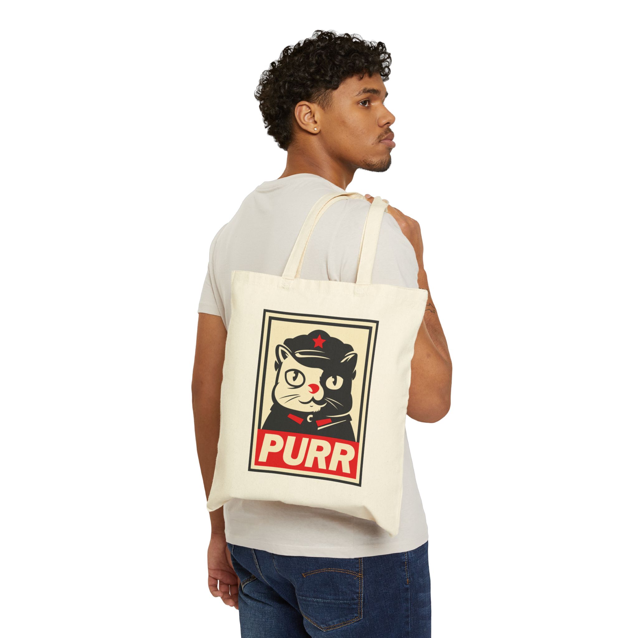 Person carrying a natural canvas tote with a black and cream cat in a military cap with a red star above a red banner inside a double poster border facing outward