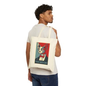 Person carrying a natural canvas tote with a hairless cat in a suit and red bow tie facing outward