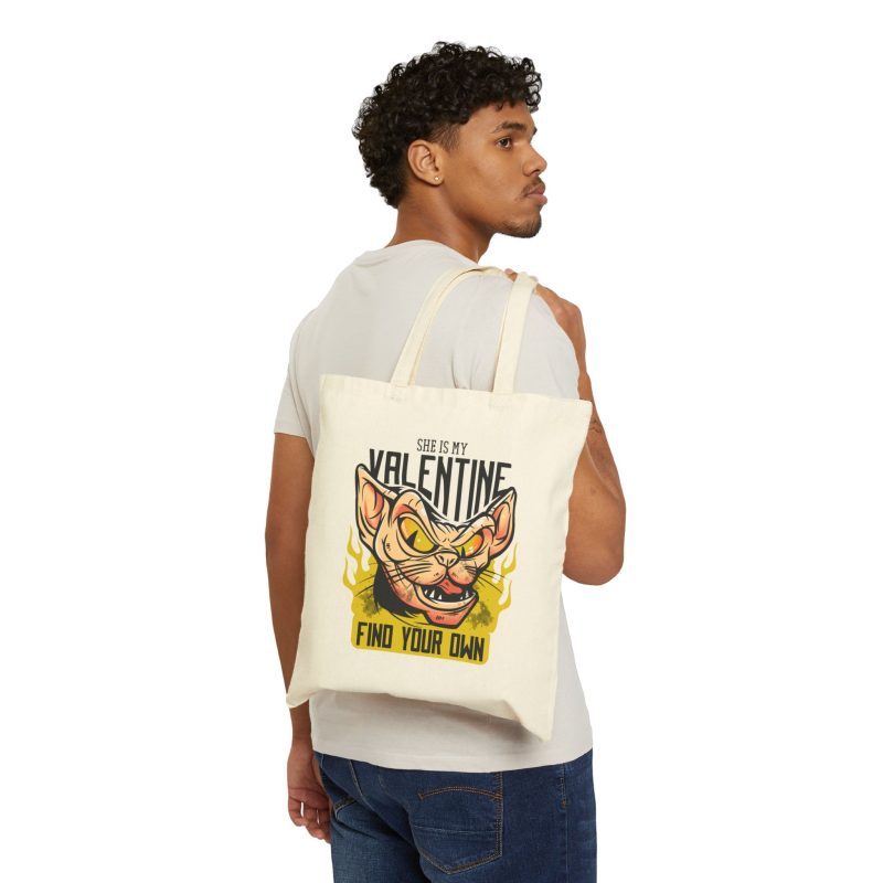 Person carrying a natural canvas tote with a fierce hairless cat with yellow eyes and flames facing outward