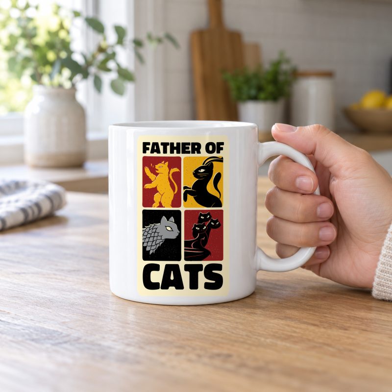 Person holding a white ceramic mug with four heraldic cat panels in red, gold, black and gray