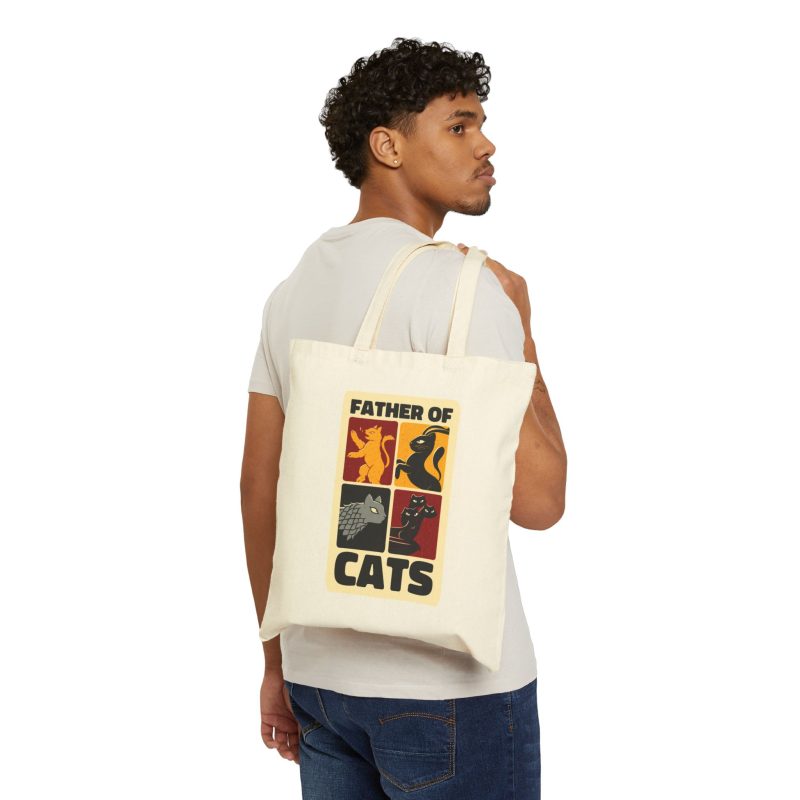 Person carrying a natural canvas tote with four heraldic cat panels in red, gold, black and gray facing outward