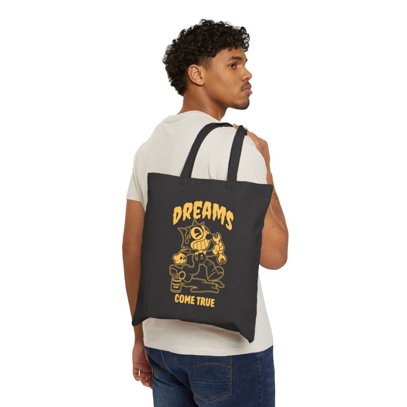 Person carrying a black canvas tote showing a grinning rubber-hose cartoon cat holding a wrench