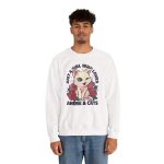 Person wearing a crewneck sweatshirt with a winking pale cream cat framed by red roses and green leaves printed on the front