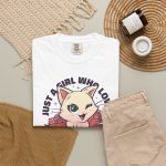 Winking pale cream cat framed by red roses and green leaves and bold lettering in the front print