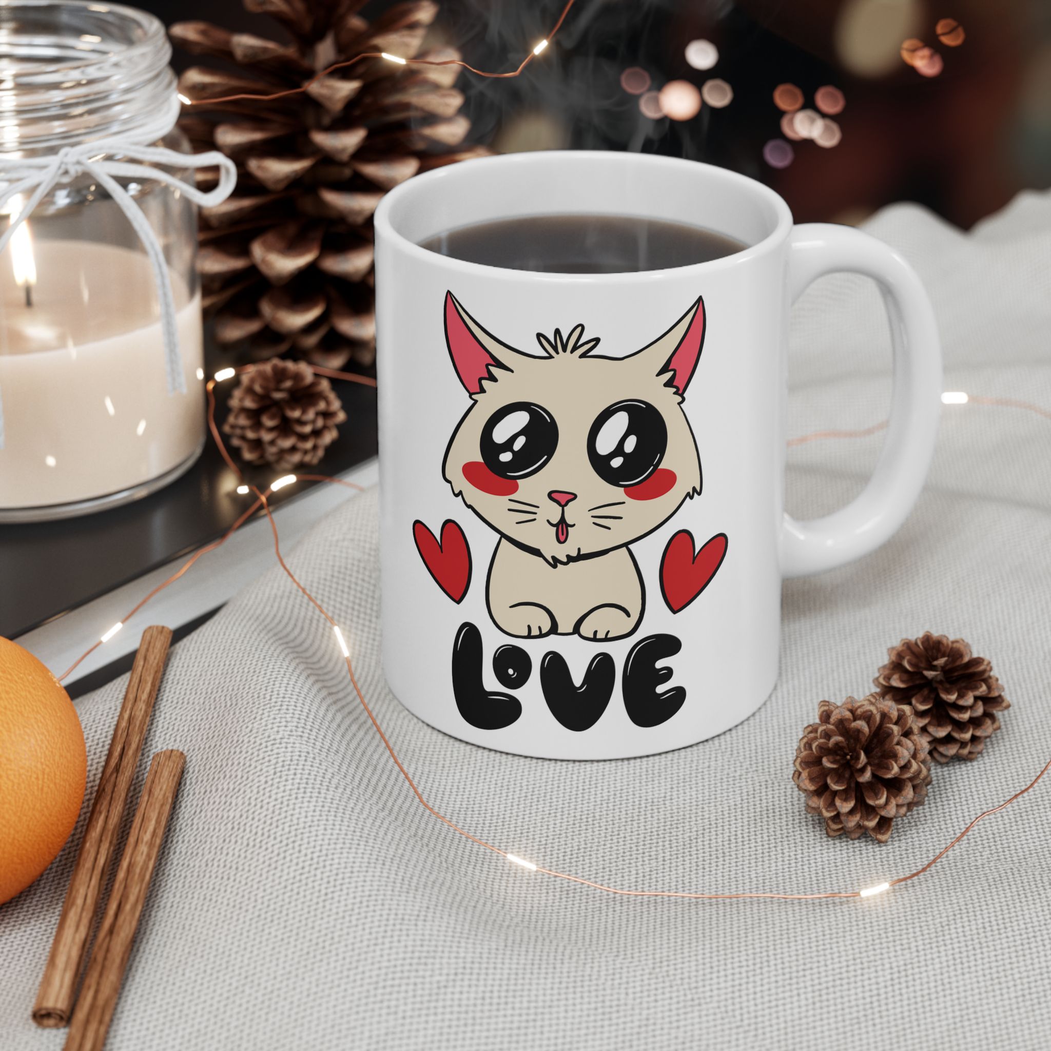 White ceramic mug showing a cream cat with glossy black eyes and red cheeks between two red hearts above black lettering