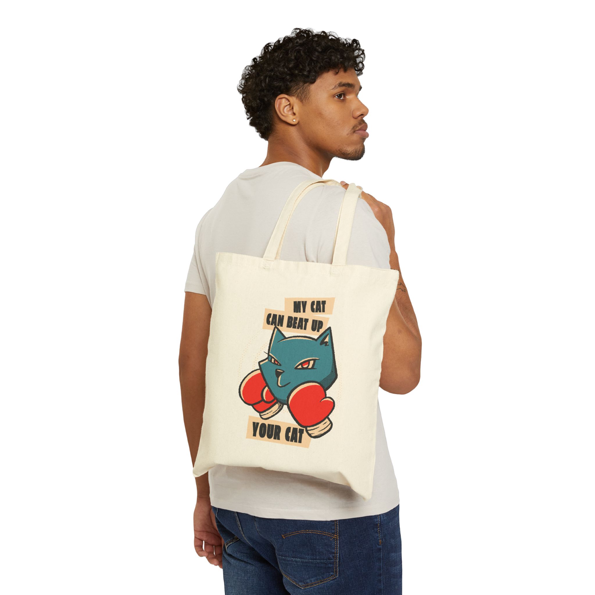 Person carrying a natural canvas tote showing a blue boxer cat with red gloves and a determined expression