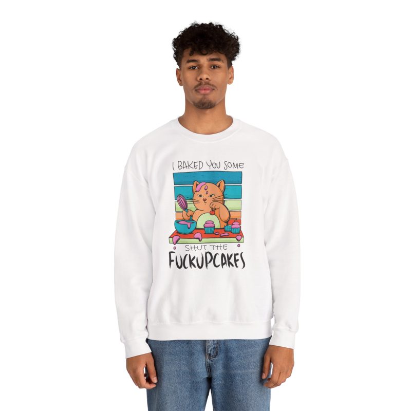 Person wearing a crewneck sweatshirt with a ginger baker cat with a pink whisk, cupcakes and turquoise retro stripes printed on the front