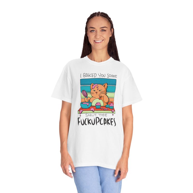 Person wearing a tee with a ginger baker cat with a pink whisk, cupcakes and turquoise retro stripes printed on the front