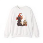 Front of the crewneck sweatshirt showing a brown cat in an orange witch hat beside a skull, lit candle and stacked spell books