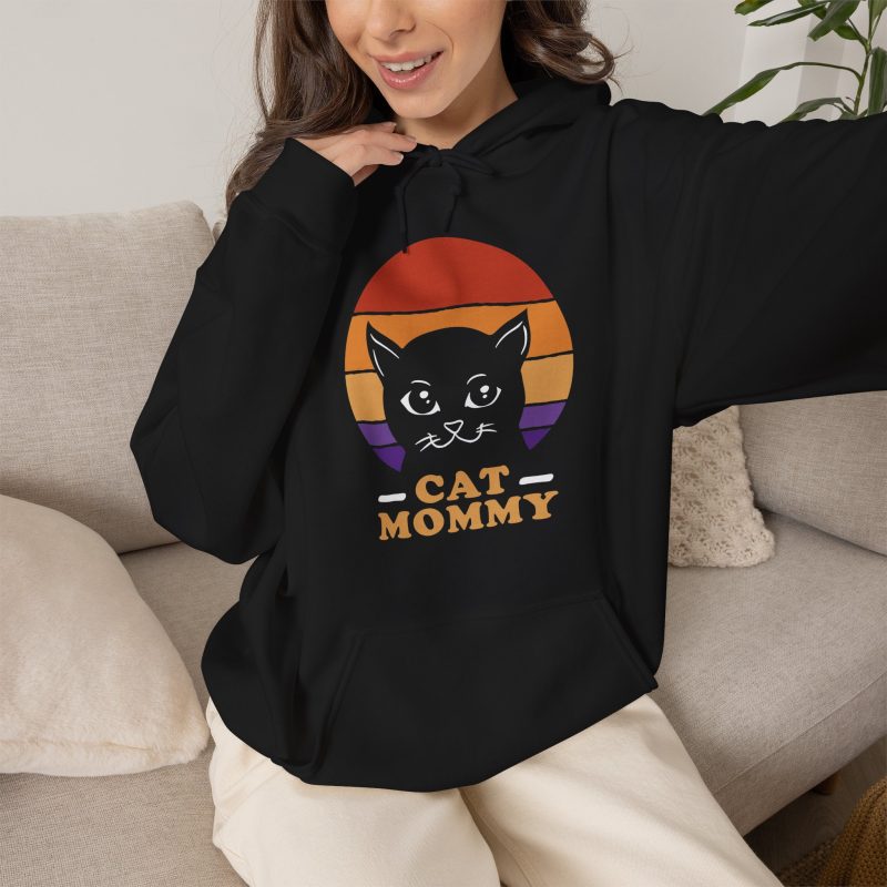 Person wearing a hoodie with a cat face inside red, orange and purple sunset stripes above warm orange lettering printed on the front