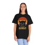 Person wearing a tee with a cat face inside red, orange and purple sunset stripes above warm orange lettering printed on the front