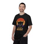 Person wearing a tee with a cat face inside red, orange and purple sunset stripes above warm orange lettering printed on the front