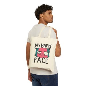 Person carrying a natural canvas tote with a pink and teal cat face and black lettering facing outward