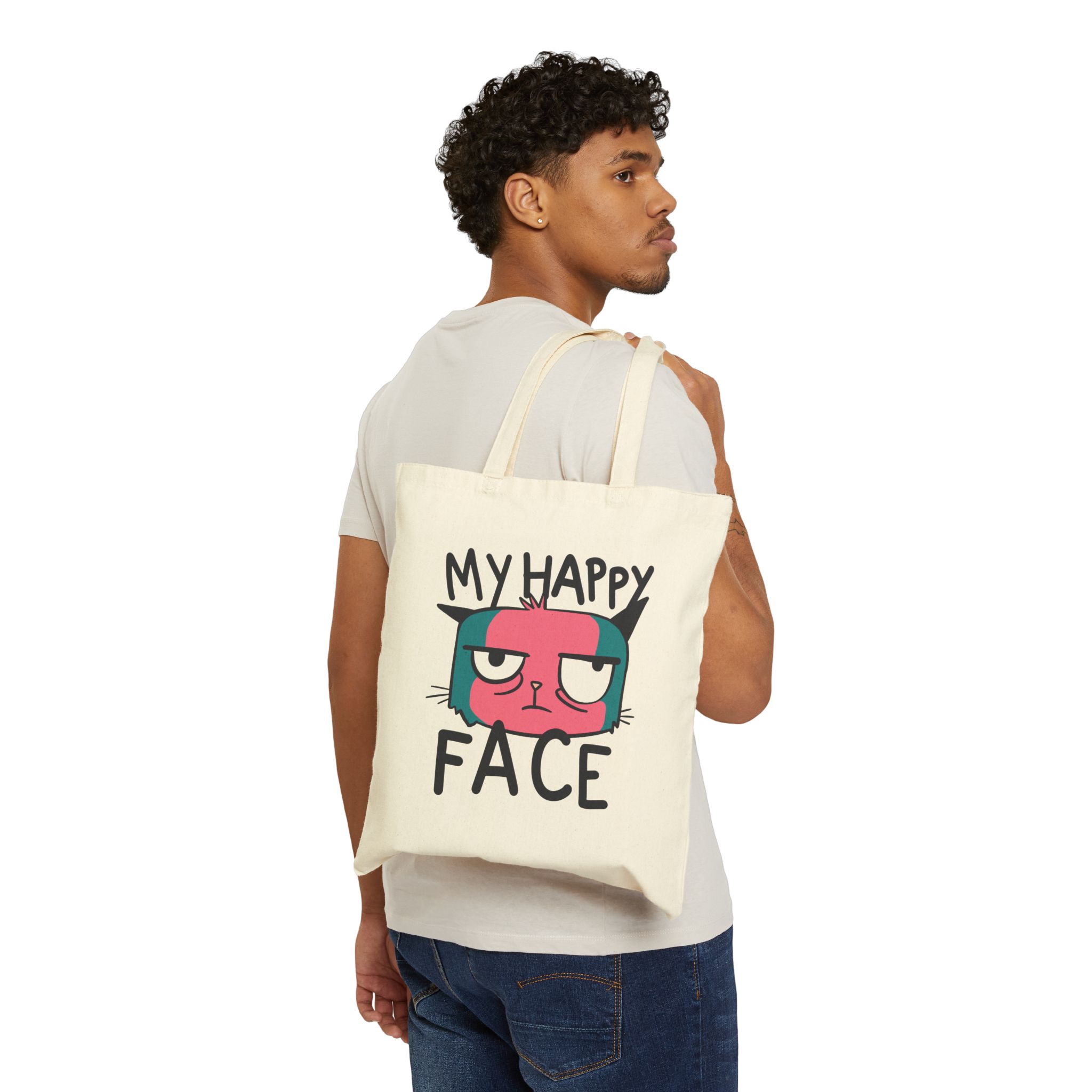 Person carrying a natural canvas tote with a pink and teal cat face and black lettering facing outward