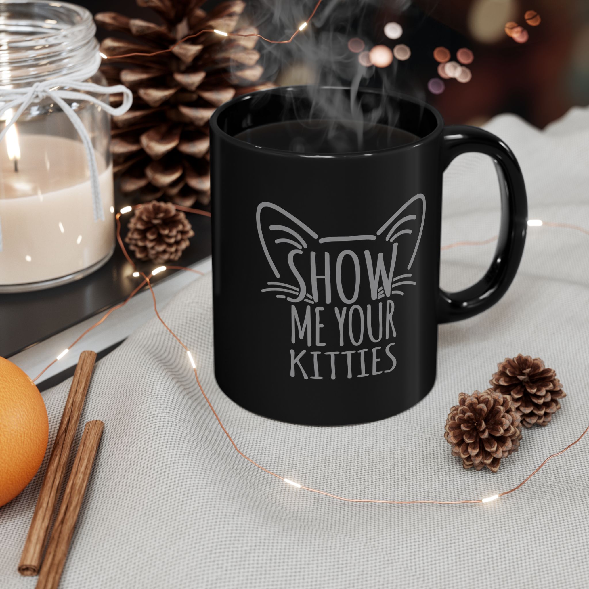 Glossy black ceramic mug showing gray cat-ear and whisker lettering