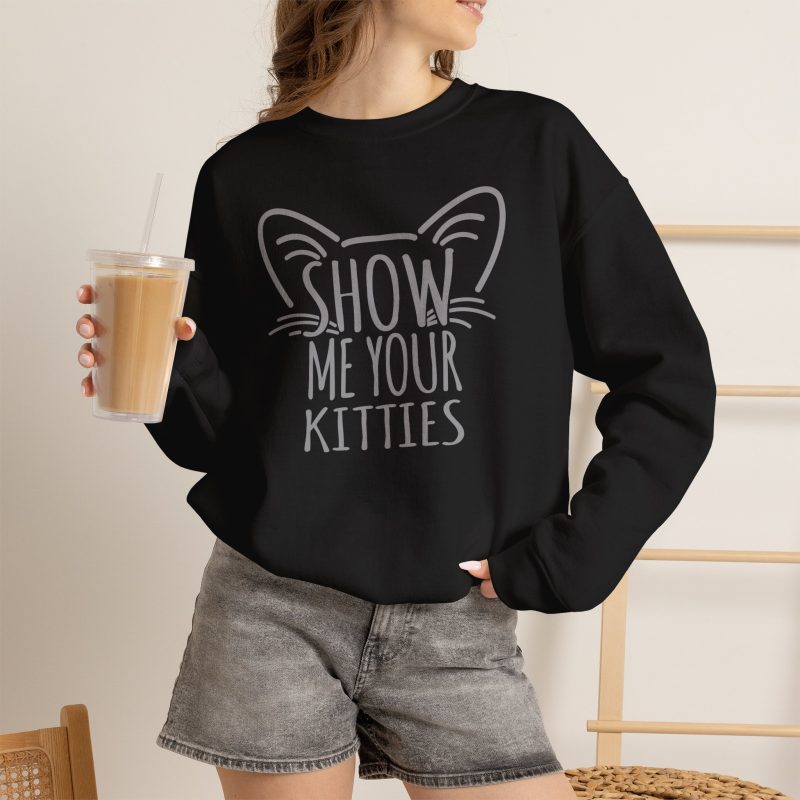 Person wearing a crewneck sweatshirt showing gray cat-ear and whisker lettering on the front