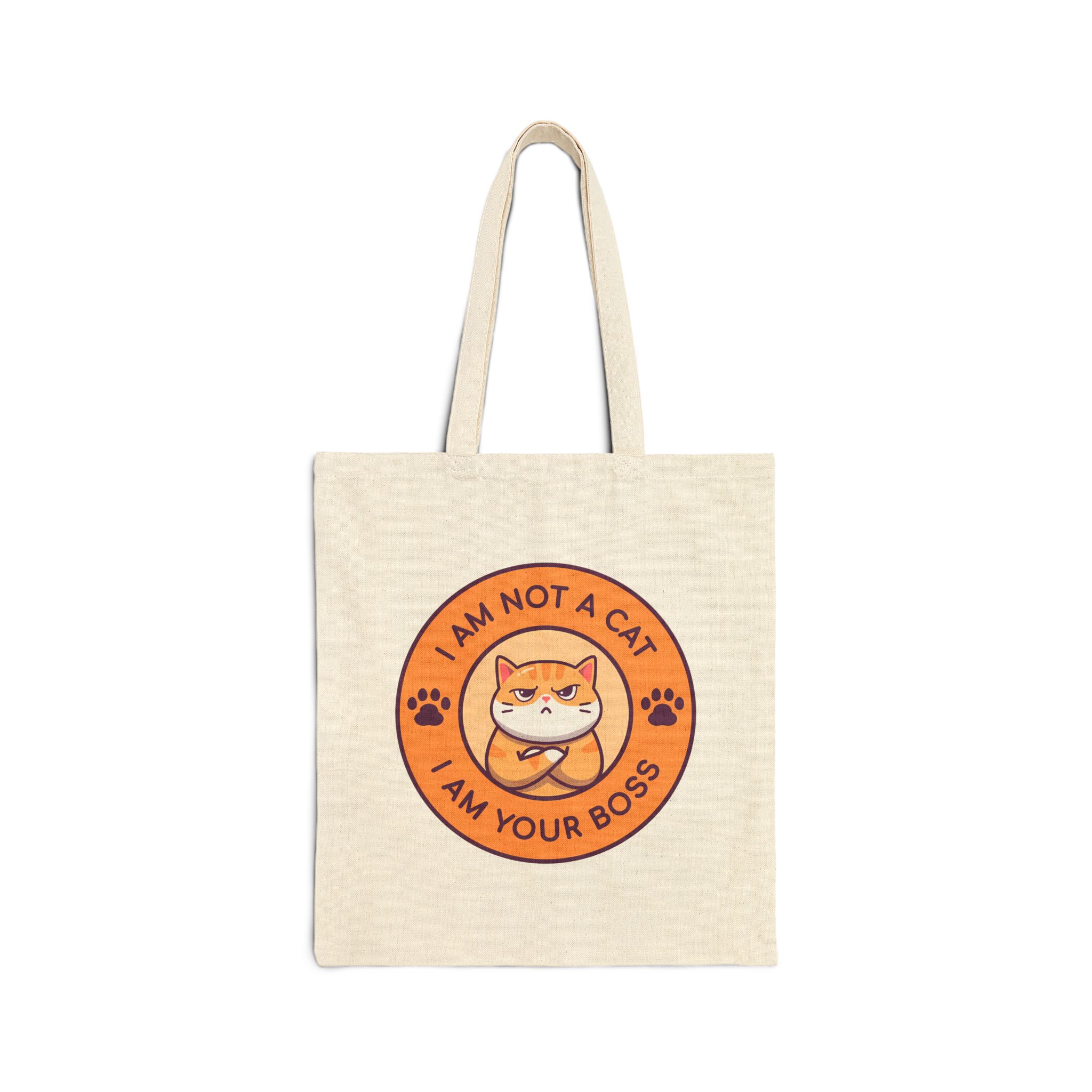 Front of the natural canvas tote showing an unimpressed ginger tabby with crossed arms inside an orange badge with dark purple lettering and two paw prints