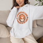 Person wearing a white hoodie with an orange tabby and coffee graphic above the front pocket