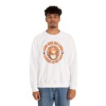Person wearing a white crewneck sweatshirt with an orange tabby and coffee graphic