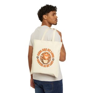 Person carrying a natural canvas tote with an orange tabby and coffee graphic facing outward