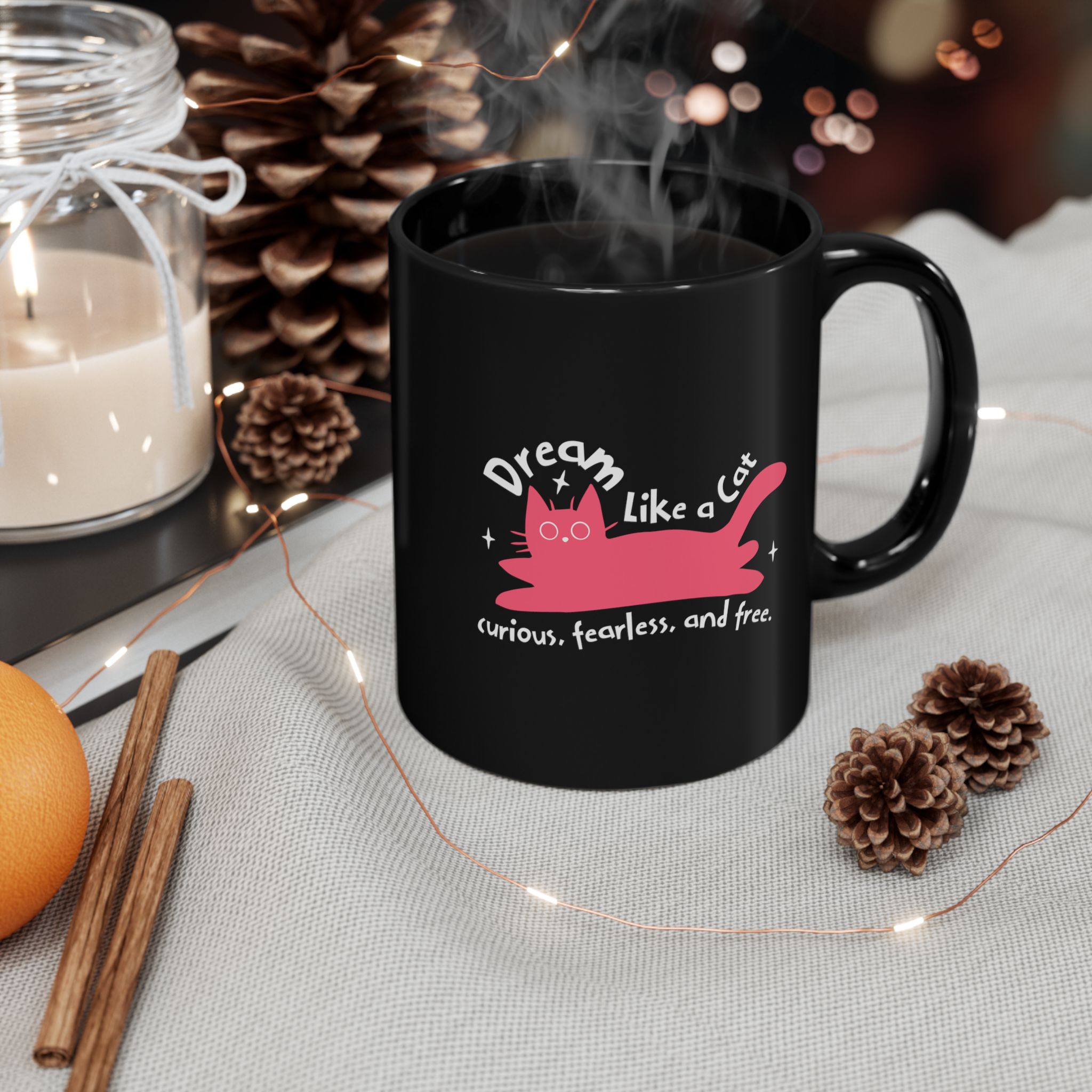 Glossy black ceramic mug showing a pink reclining cat with a raised tail, round eyes and white sparkles