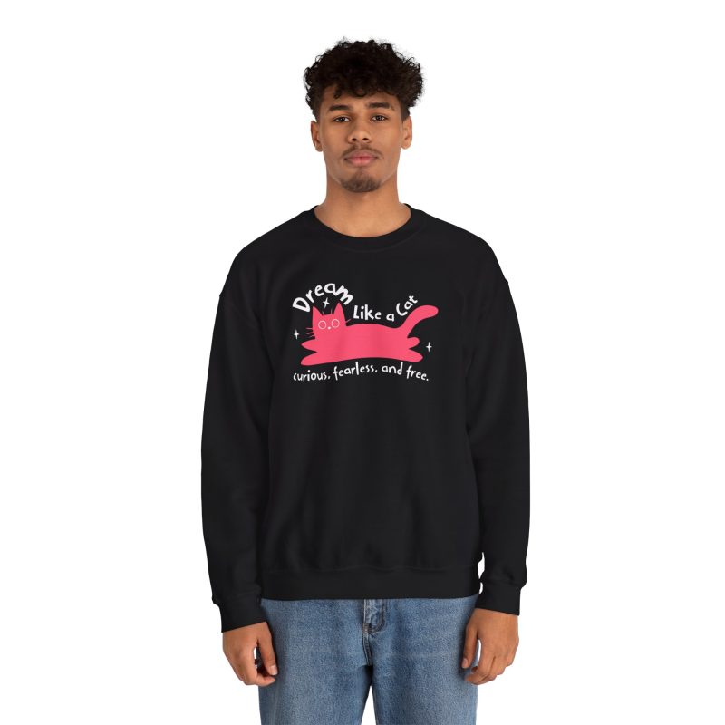 Person wearing a crewneck sweatshirt with a pink reclining cat with a raised tail, round eyes and white sparkles printed on the front