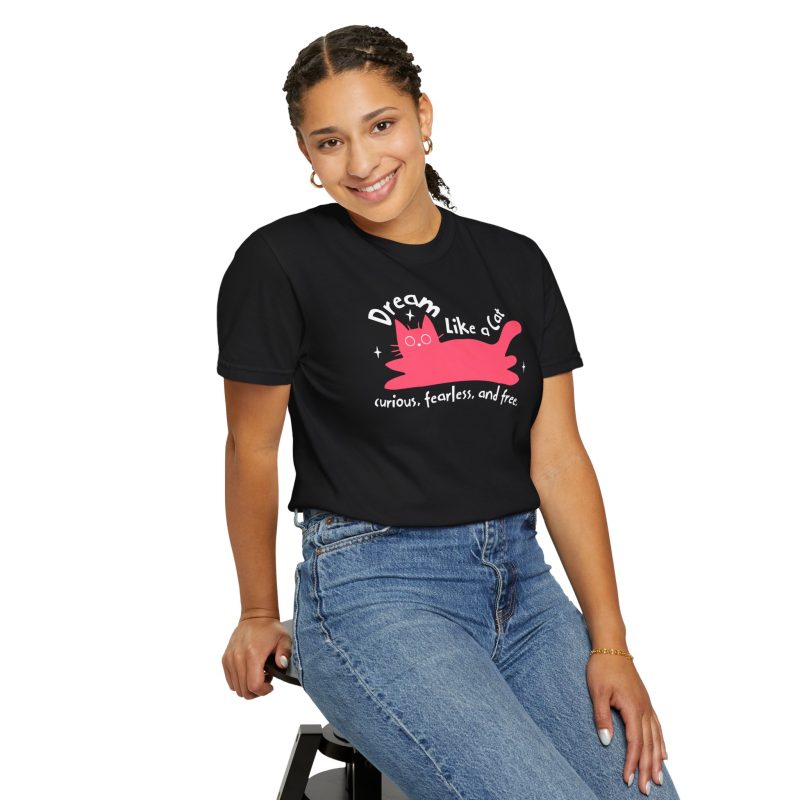 Person wearing a tee with a pink reclining cat with a raised tail, round eyes and white sparkles printed on the front
