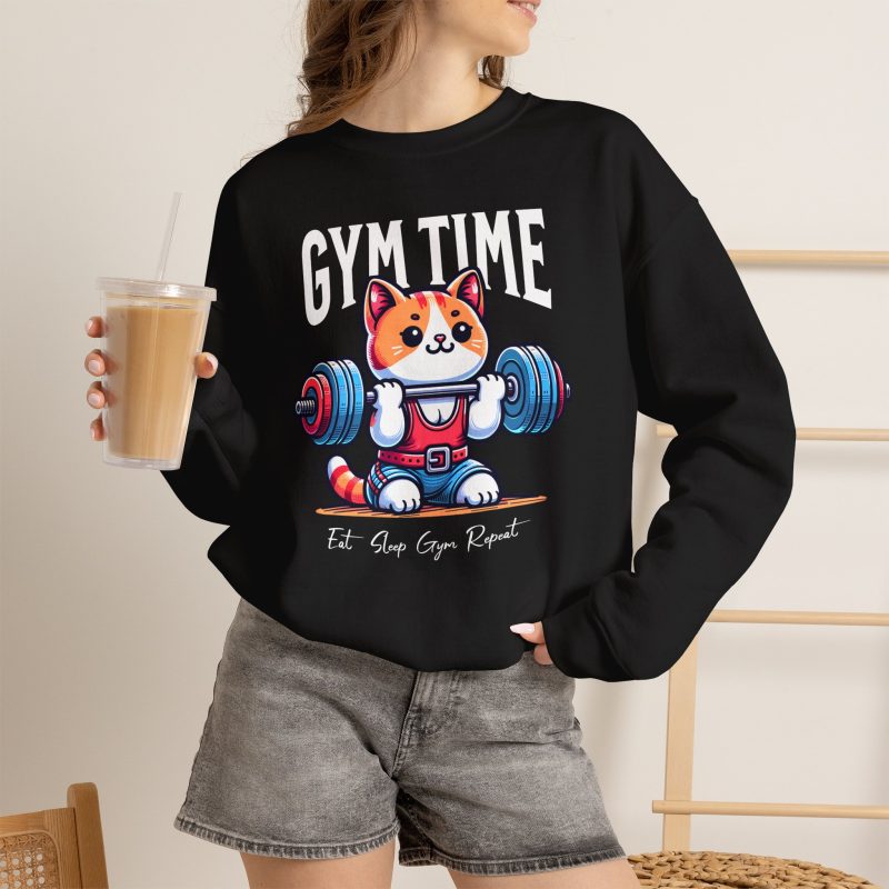 Person wearing a crewneck sweatshirt with an orange-and-white kitten lifting a barbell with blue and pink weight plates printed on the front