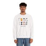 Person wearing a crewneck sweatshirt with eight line-drawn cats in two rows with different expressions and coat patterns printed on the front