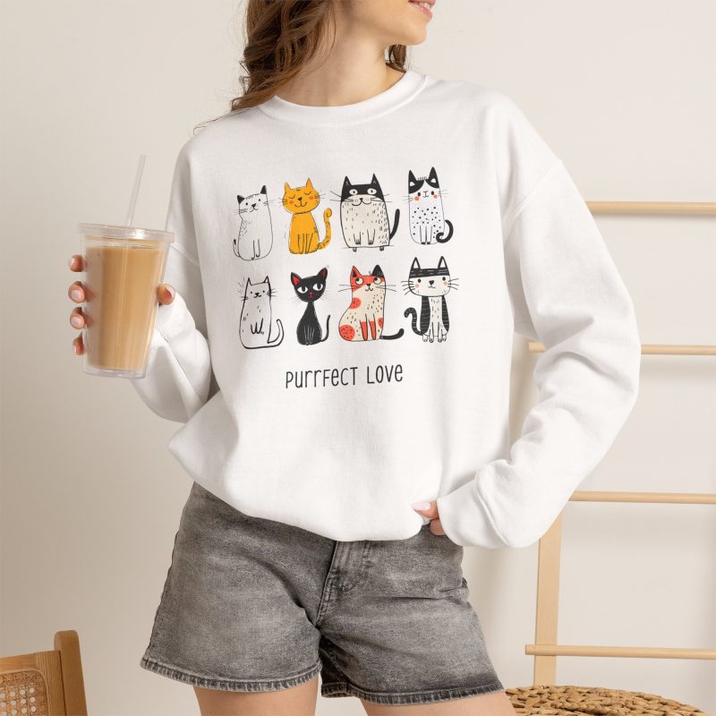 Person wearing a crewneck sweatshirt with eight line-drawn cats in two rows with different expressions and coat patterns printed on the front
